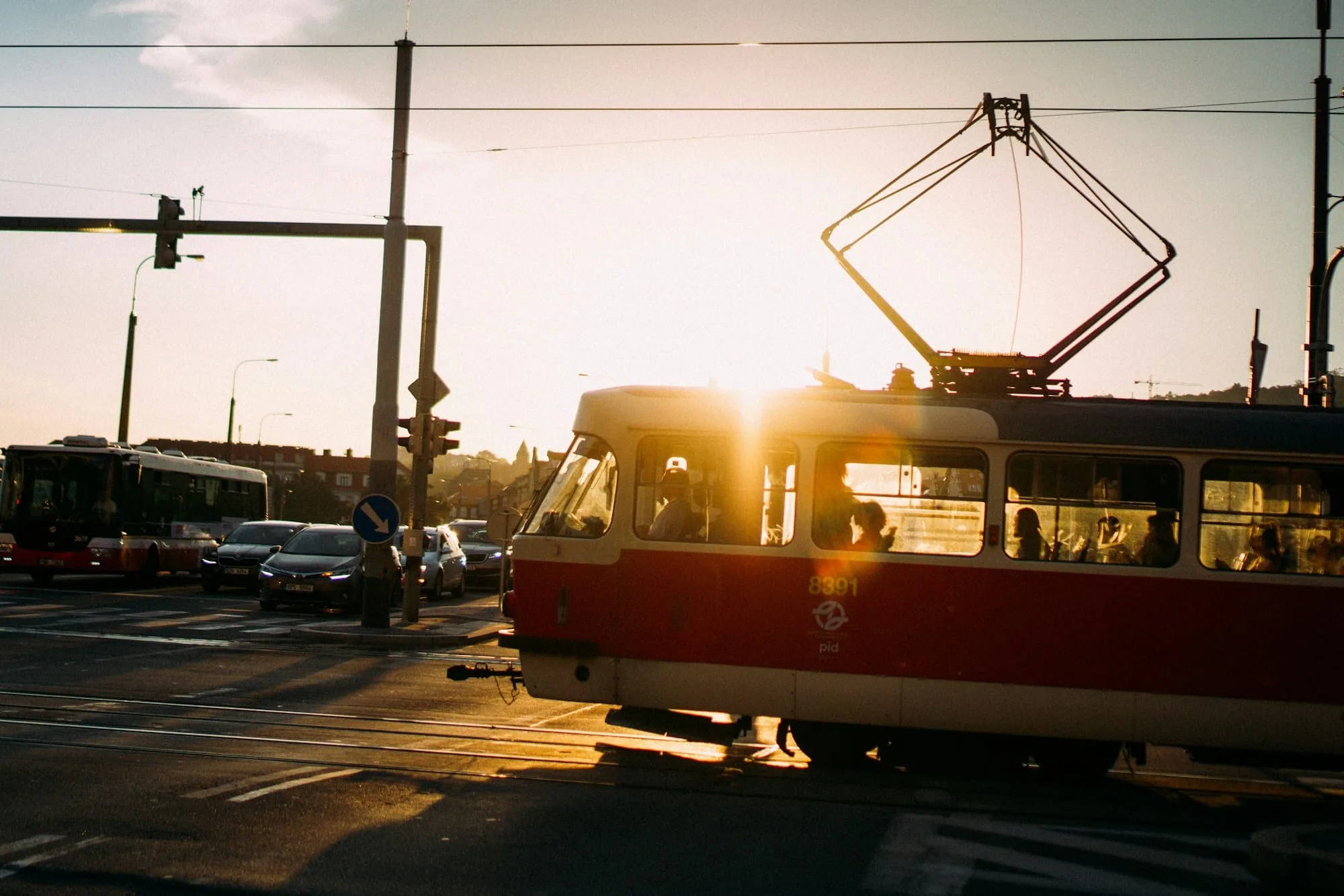 A vintage red tram crossing a European city street at sunset